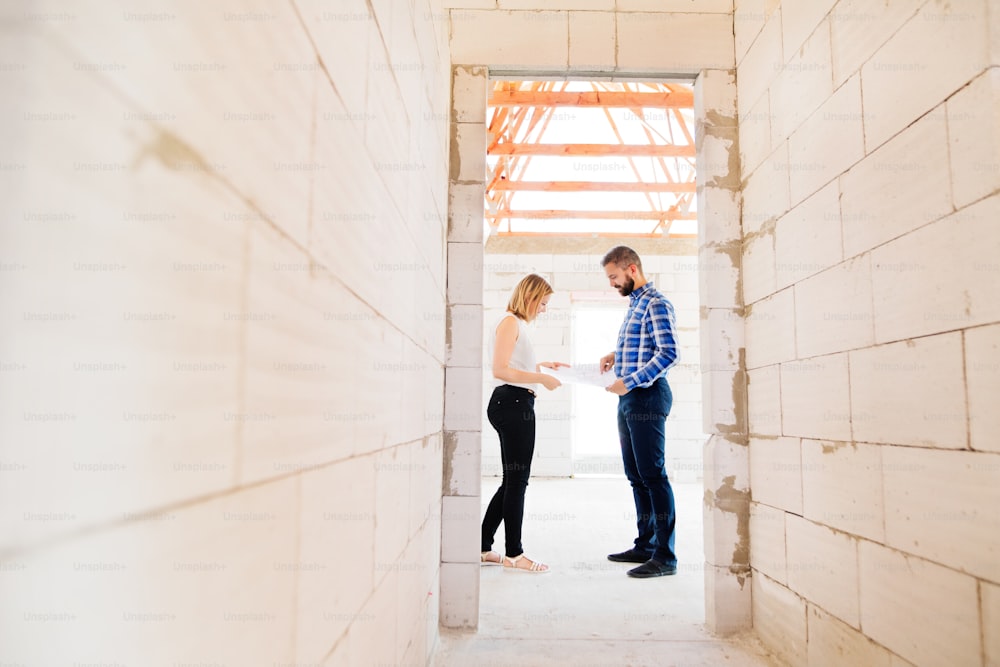 若い夫婦や建築家、土木技師が新しい家の計画を見て、建設現場で問題を議論する。