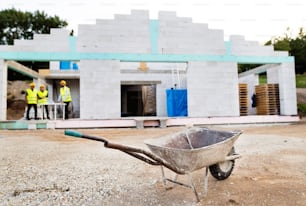 Architect, civil engineer and worker at the construction site. Close up of wheelbarrow.