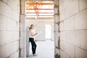 Schöner junger Architekt oder ein Hausbesitzer, der sich Blaupausen ansieht und Probleme auf der Baustelle kontrolliert.