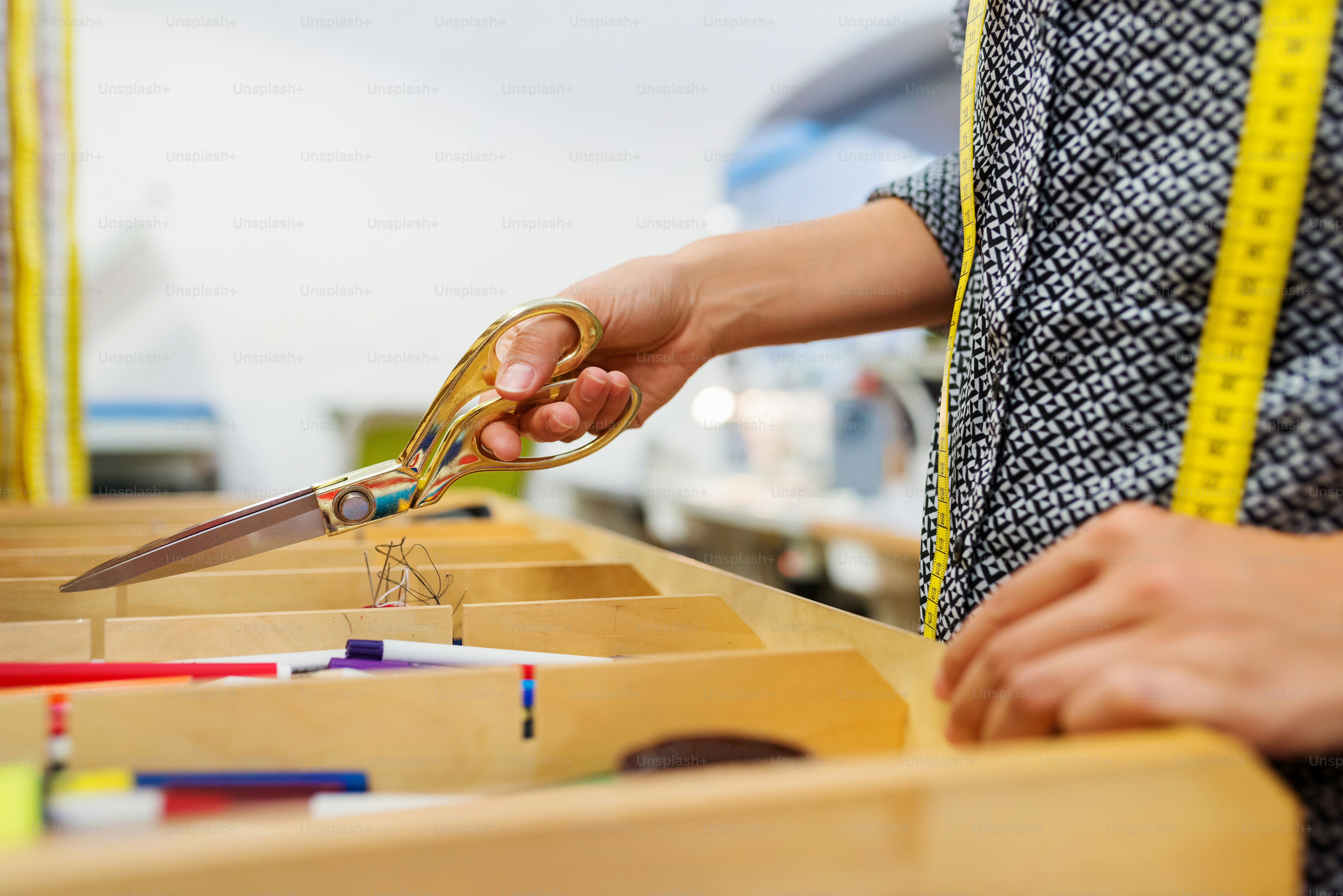 Close up of hands of unrecognizable tailor woman taking scissors out of a drawer