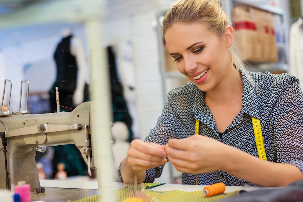 Beautiful young woman sewing clothes with sewing machine.