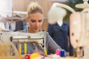 Hermosa joven cosiendo ropa con máquina de coser.