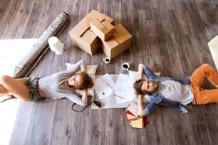 새 집으로 이사하는 젊은 부부는 골판지 상자 근처 바닥에 누워 커피를 마신다.