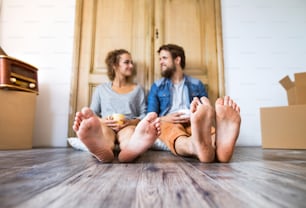 Young married couple moving in new house, sitting on the floor, resting.
