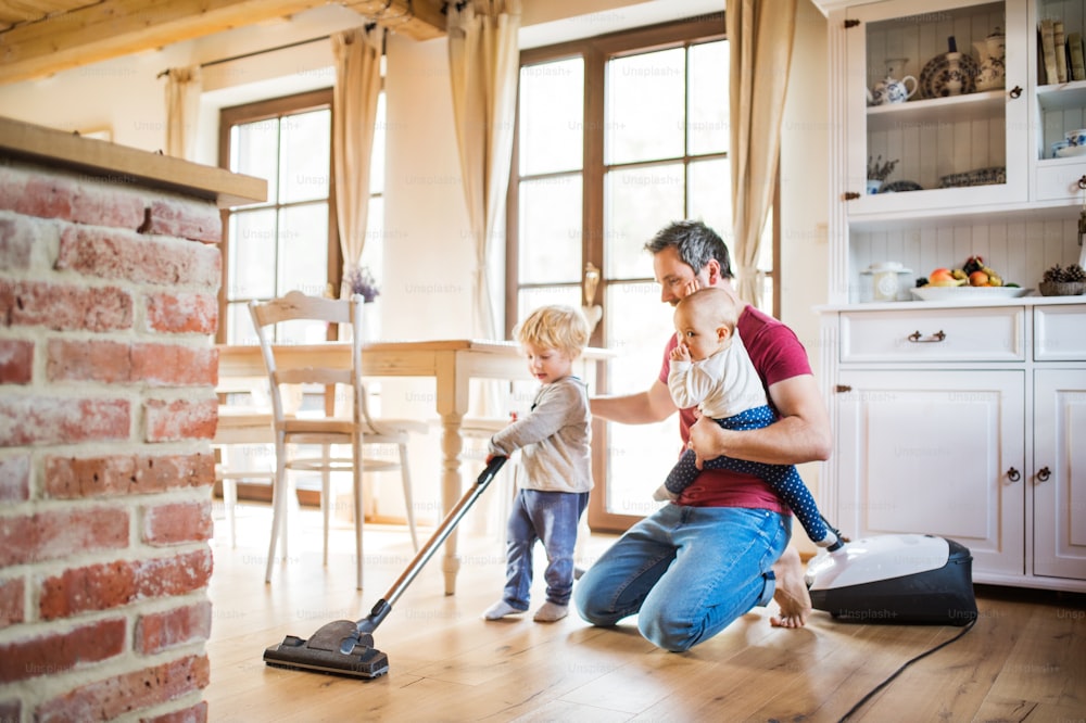Padre y dos niños pequeños haciendo las tareas domésticas. Paternidad.