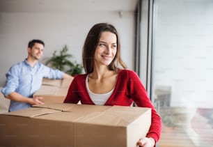 Young happy couple with cardboard boxes moving in a new home.