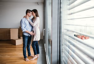 Young happy couple with cardboard boxes moving in a new home, hugging. Copy space.