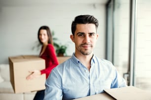 Young happy couple with cardboard boxes moving in a new home.