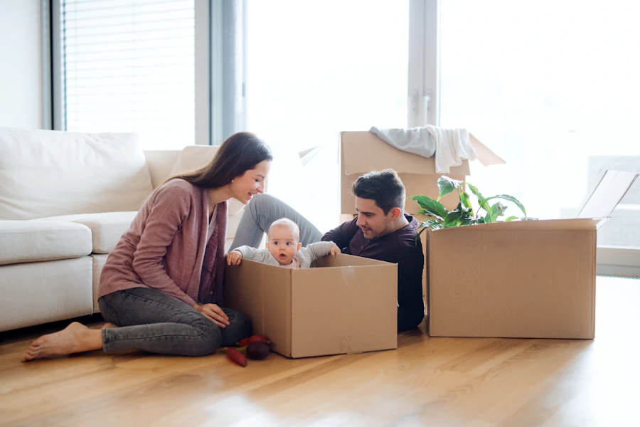 Happy young couple with baby and moving boxes in their new home