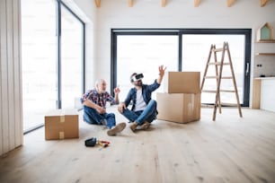 Ein reifer Mann mit VR-Brille und sein älterer Vater richten ein neues Haus ein, ein neues Wohnkonzept.