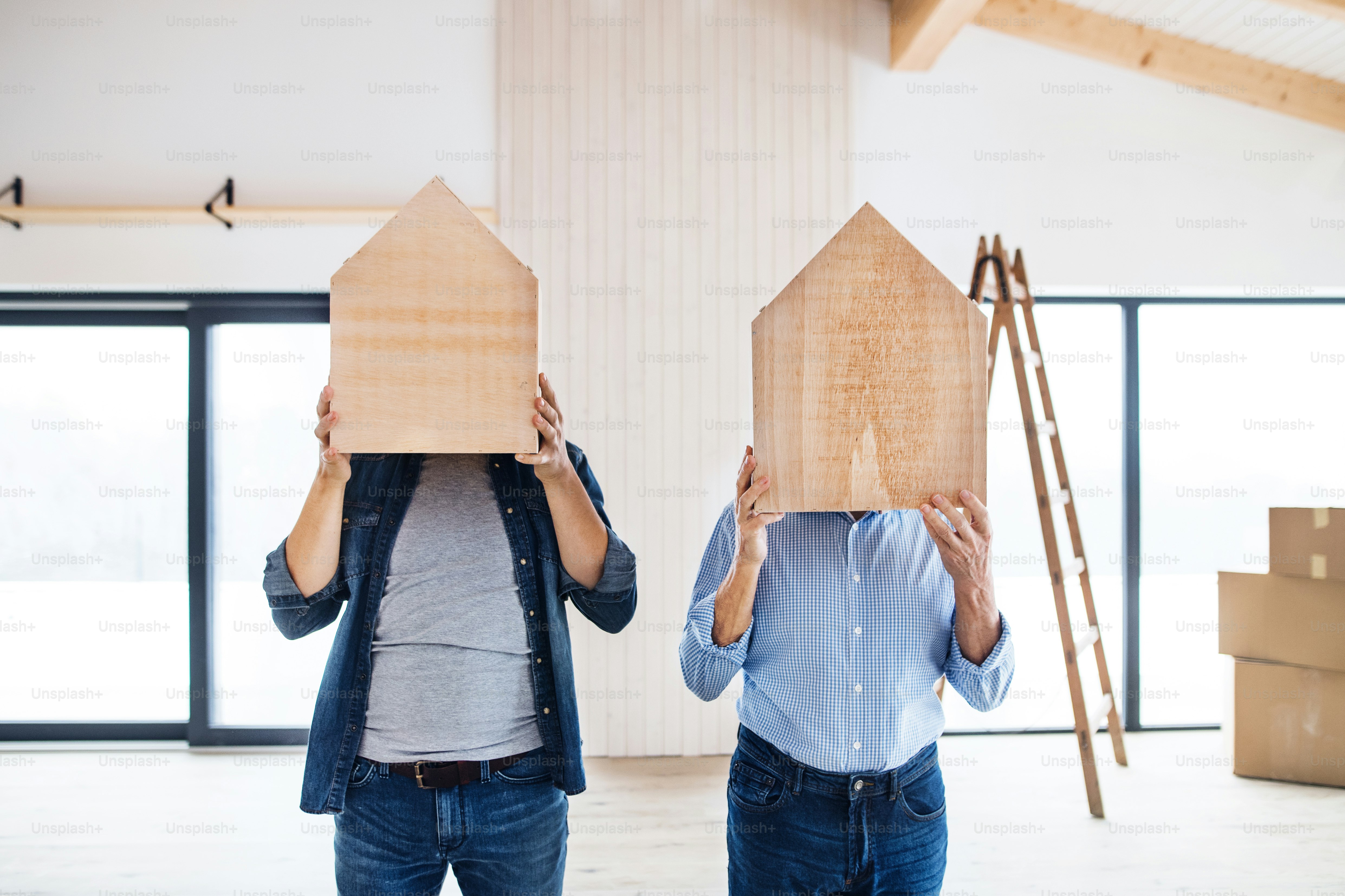 A senior man helping his mature son with furnishing new house, having ...