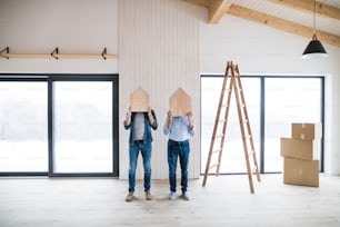 Two men holding small wooden houses on their heads when furnishing new house, a new home concept.