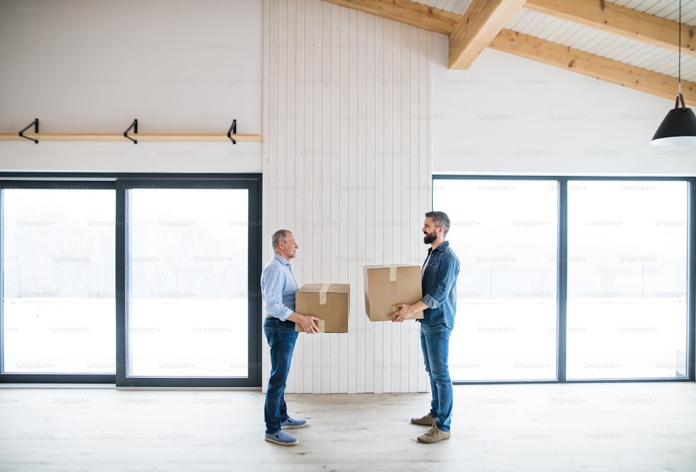 Two men holding cardboard boxes in front of them when furnishing new house, a new home concept.