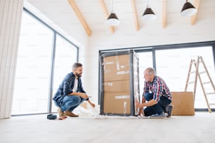 A cheerful senior man helping his mature son with furnishing new house, a new home concept.