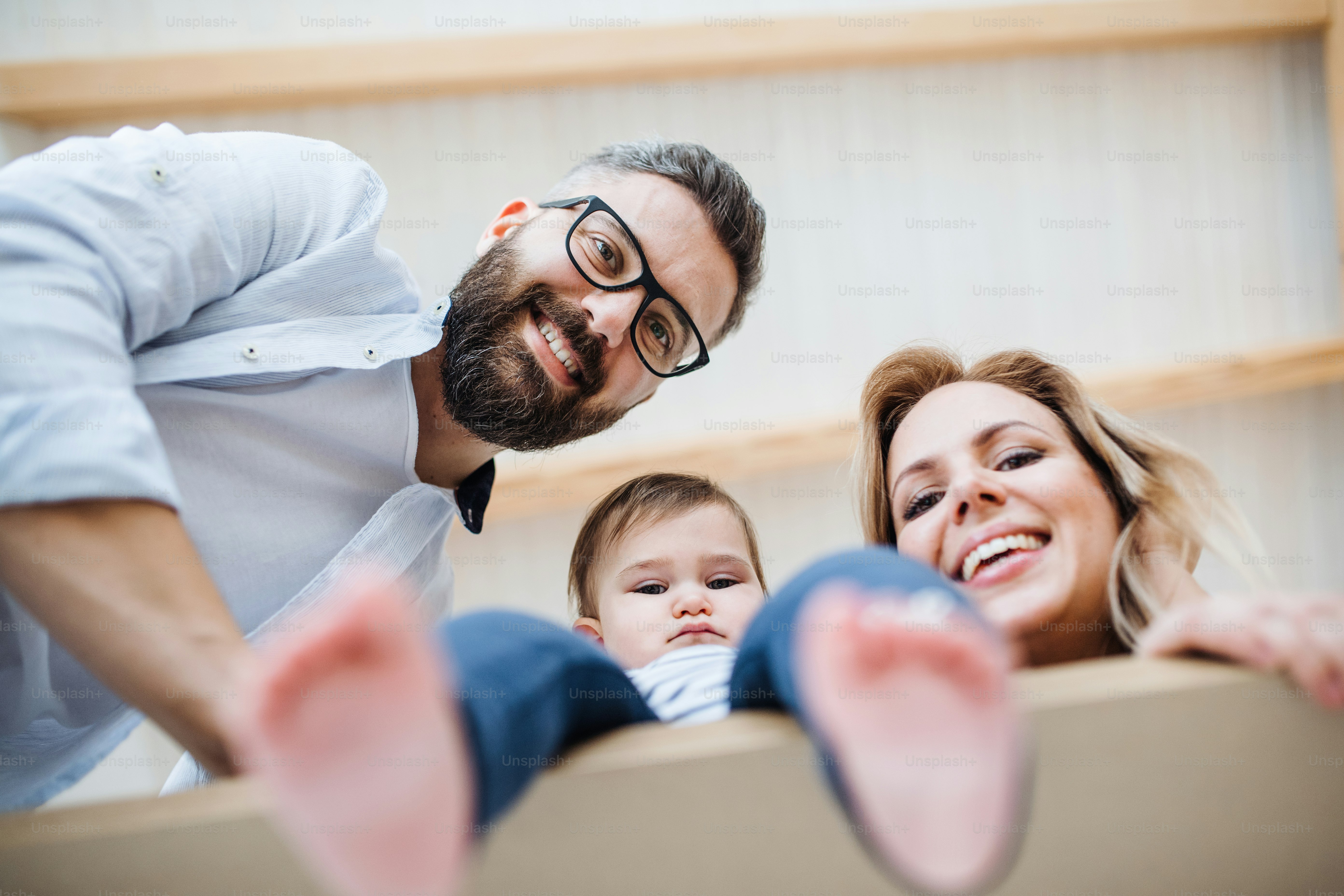 Una vista de bajo ángulo de una familia joven y feliz con una niña pequeña que se muda a un nuevo hogar.