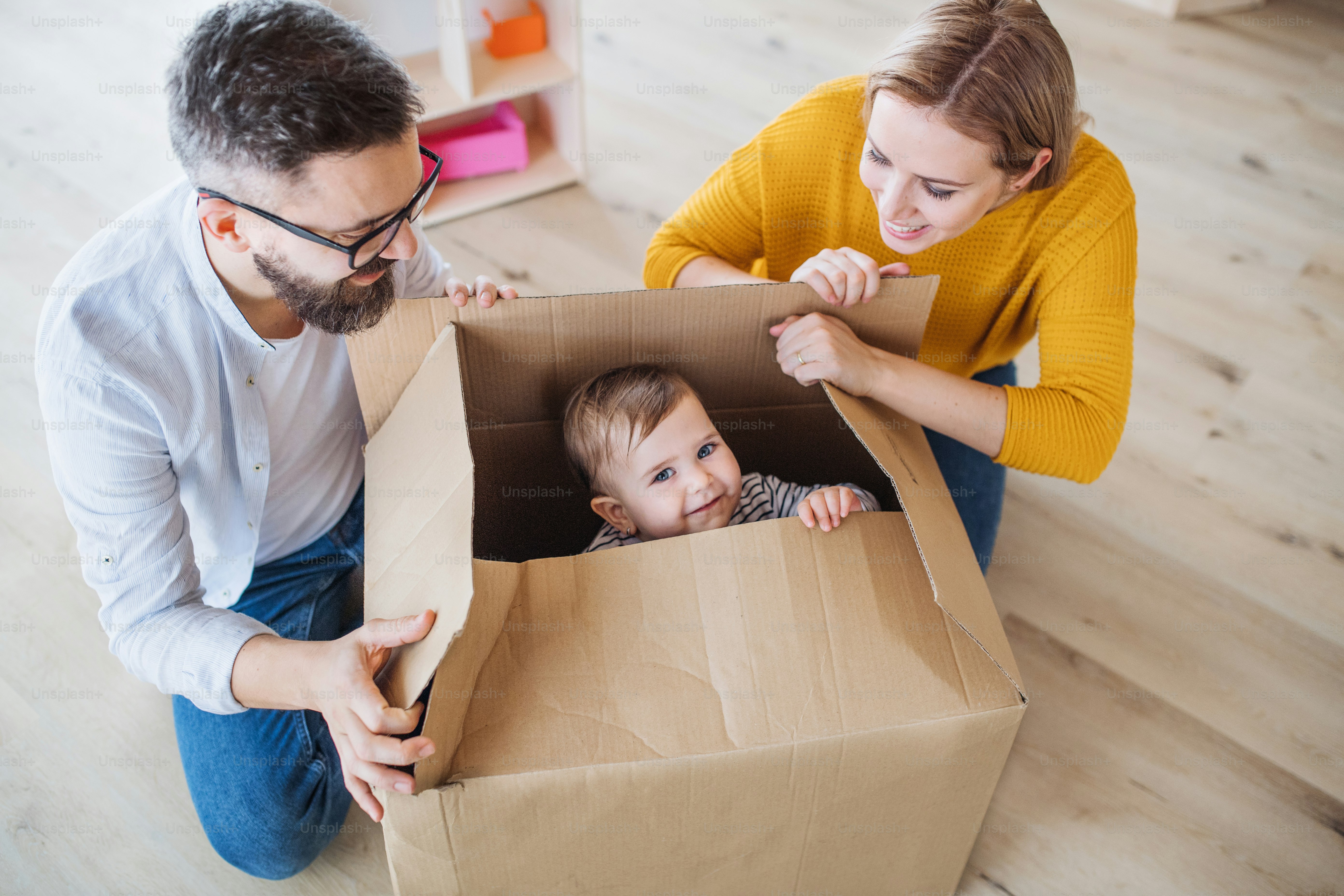 Una vista superior de una familia joven feliz con una niña pequeña que se muda a un nuevo hogar.