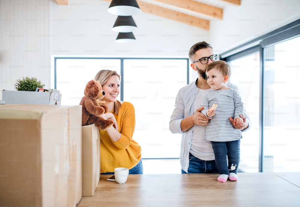 Un ritratto di giovane famiglia felice con una bambina che si trasferisce in una nuova casa.