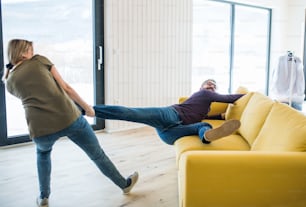 A young happy couple furnishing new house, having fun. A moving in new home concept.