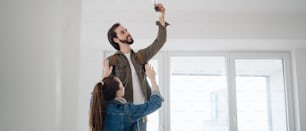 A young couple changing light bulb in new flat, moving, new home and relocation concept.