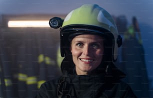 Eine mittelerwachsene Feuerwehrfrau, die nachts in der Feuerwache in die Kamera schaut.