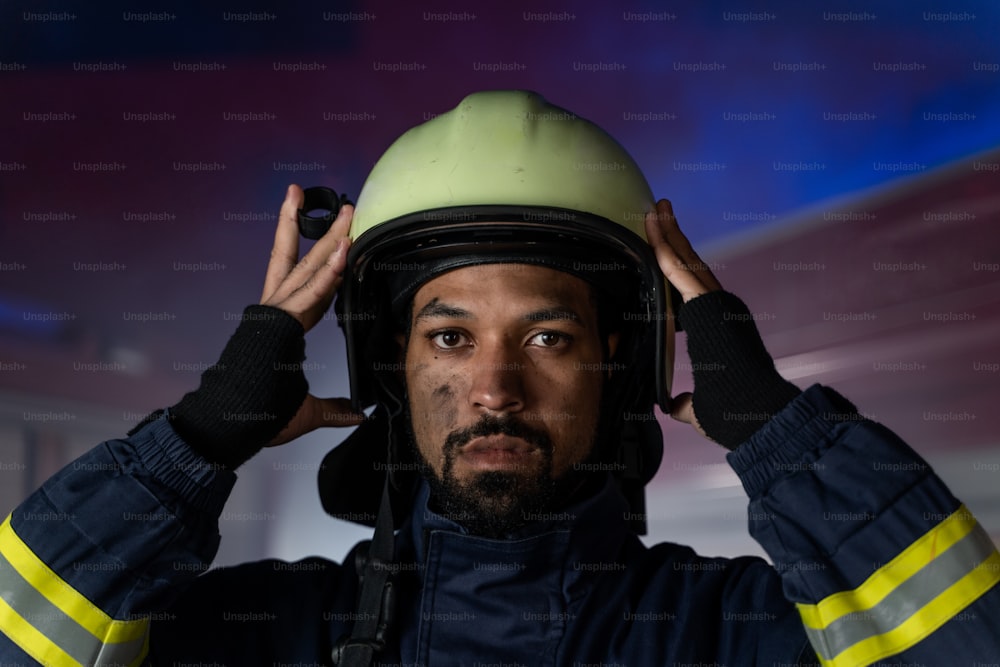 Un ritratto di sporco vigile del fuoco in servizio con camion dei pompieri sullo sfondo di notte, guardando la macchina fotografica.