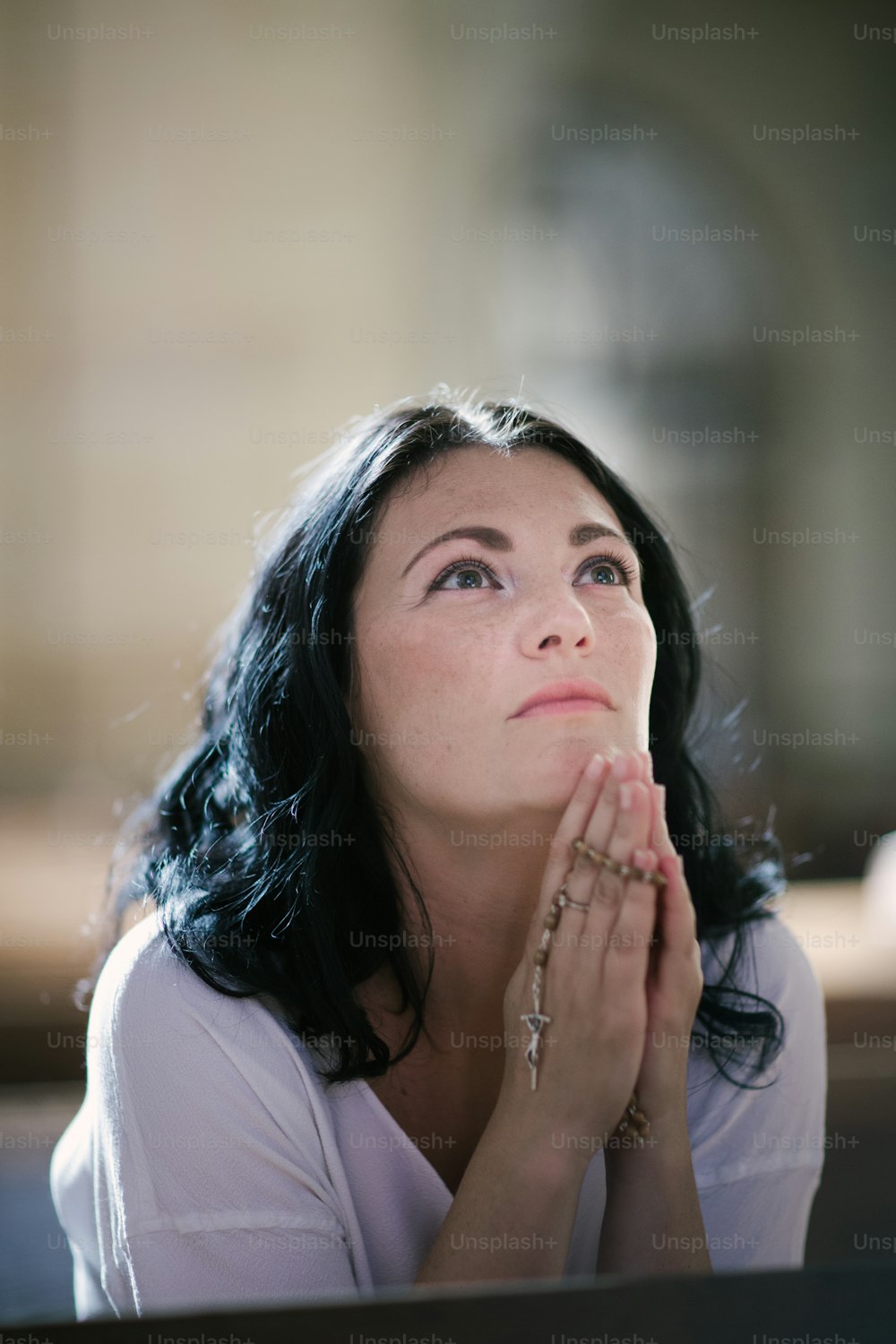 교회에서 묵주를 들고 기도하는 아름다운 여자