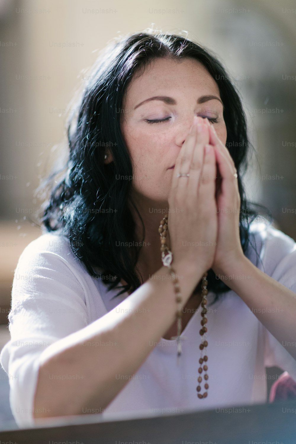 Mulher bonita com um rosário rezando na igreja