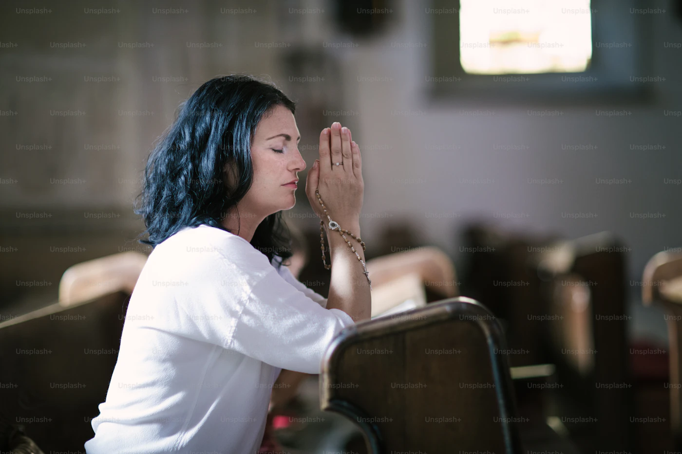 A woman praying quietly in a church pew