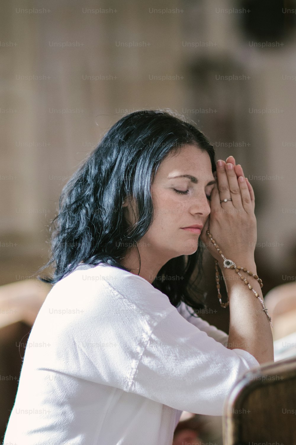 Schöne Frau mit einem Rosenkranz betet in der Kirche