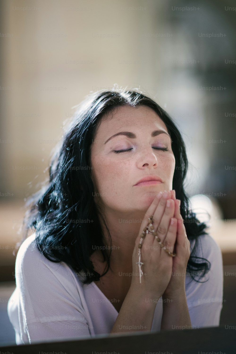 Schöne Frau mit einem Rosenkranz betet in der Kirche