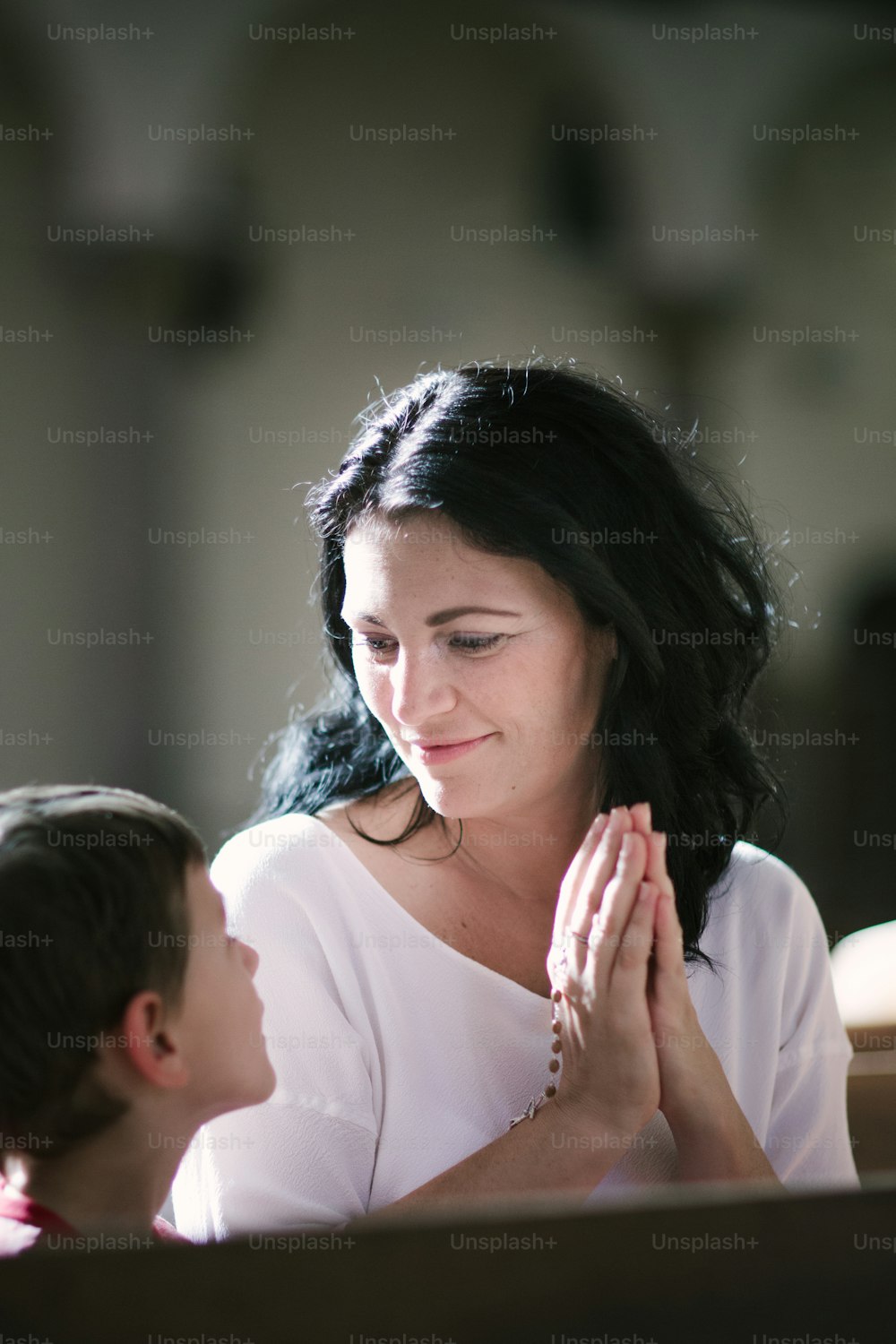 Mulher bonita com seu filho orando na igreja