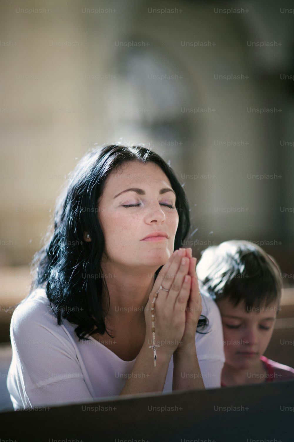 교회에서 기도하는 아들과 함께 있는 아름다운 여자