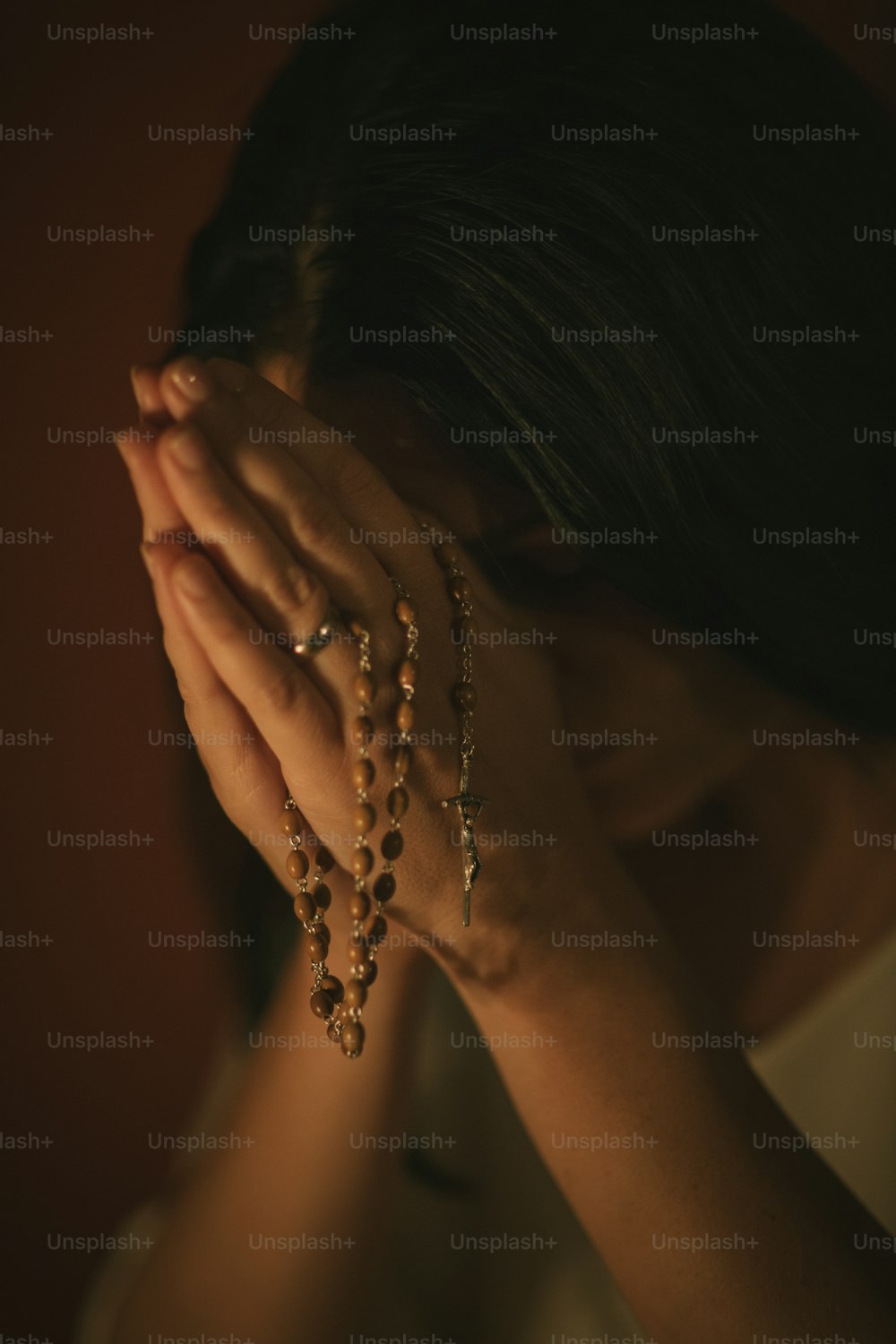 Mulher irreconhecível com um rosário rezando na igreja