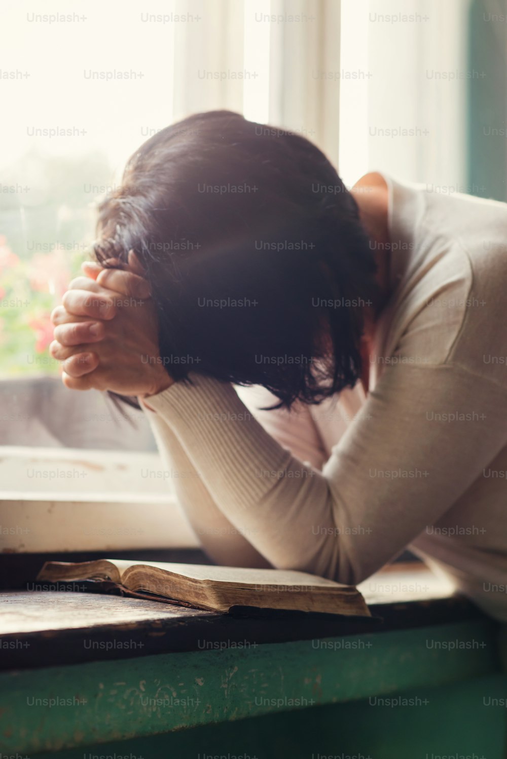 Femme méconnaissable lisant sa Bible et priant