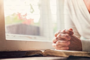 Mãos de uma mulher irreconhecível com a Bíblia orando