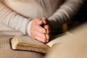 Mulher irreconhecível segurando uma bíblia em suas mãos e orando