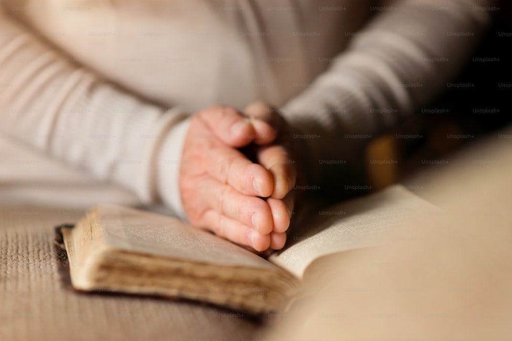 Mujer irreconocible sosteniendo una Biblia en sus manos y orando