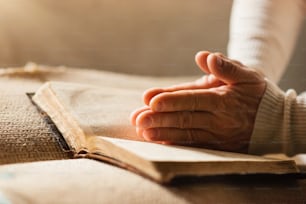 Unrecognizable woman holding a bible in her hands and praying