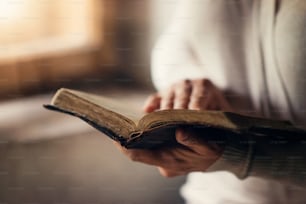 Unkenntliche Frau, die eine Bibel in den Händen hält und betet