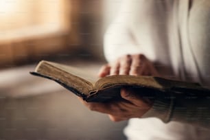 Femme méconnaissable tenant une bible dans ses mains et priant