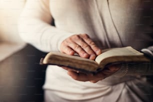 Femme méconnaissable tenant une bible dans ses mains et priant