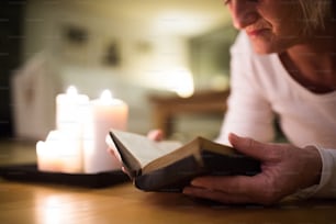 Unkenntliche Frau, die auf dem Boden liegt und ihre Bibel liest. Brennende Kerzen neben ihr. Aufschließen.