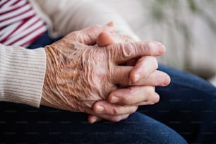 Pregando le mani rugose di una donna anziana a casa. Primo piano.