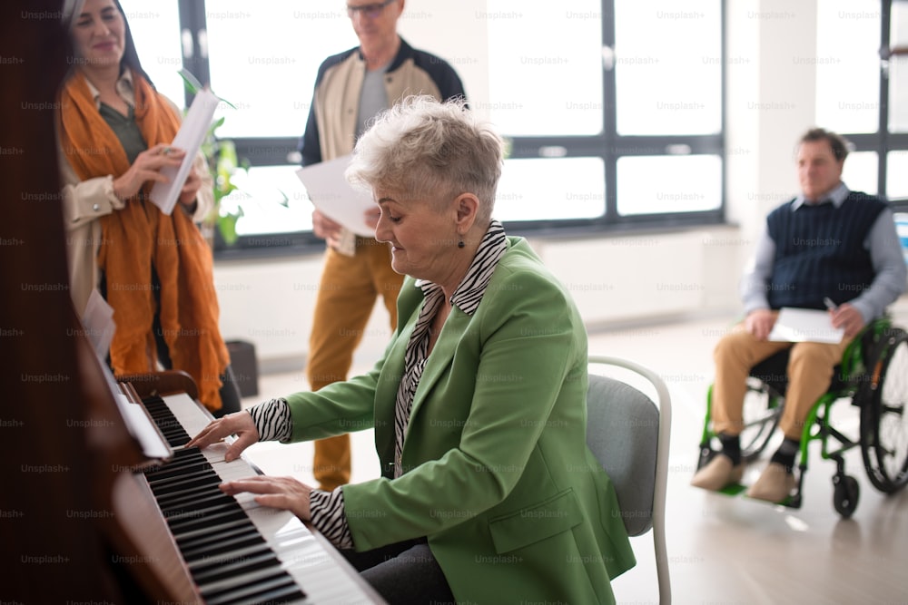 Una mujer mayor tocando el piano en el ensayo del coro.