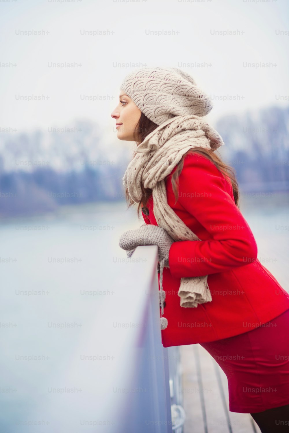 Winter outdoor portrait of pregnant woman in fashionable clothes standing by the river