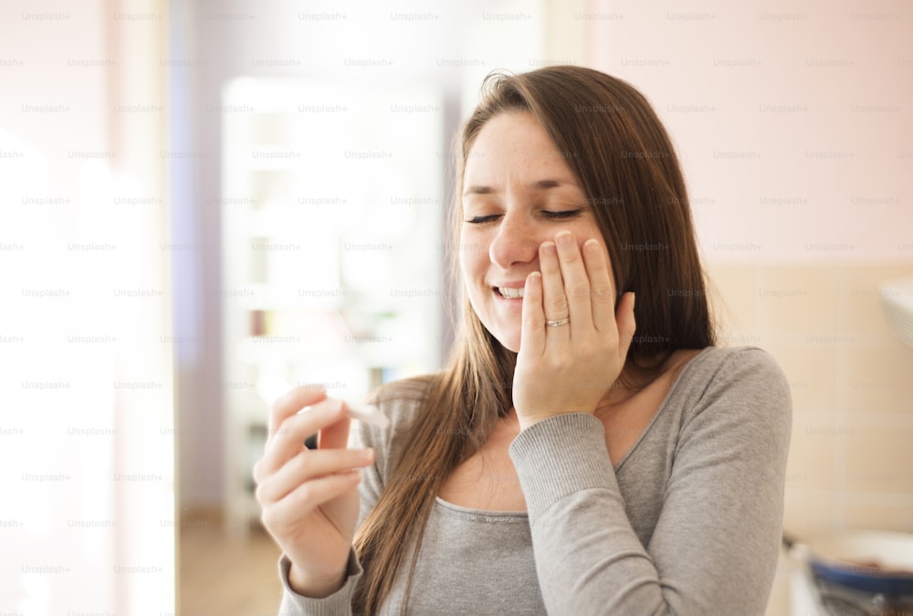 Happy woman with positive pregnancy test result. She is excited at home.