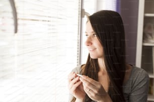 Happy woman with positive pregnancy test result. She is excited at home.