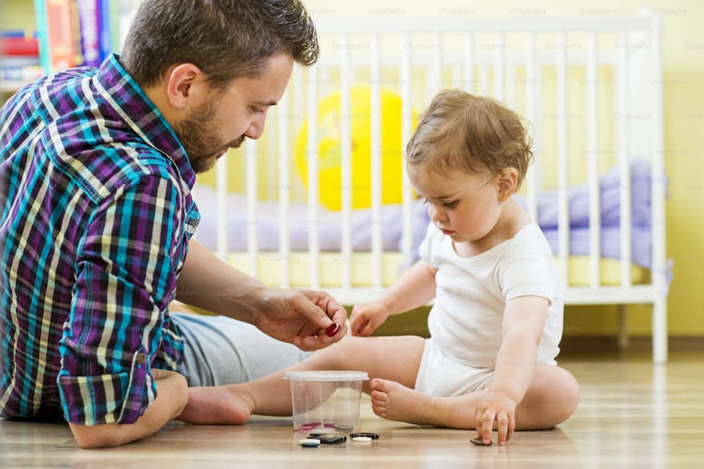 happy father and his little daughter playing with various buttons at home