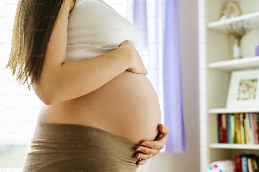 Gros plan d’une femme enceinte méconnaissable avec les mains sur le ventre