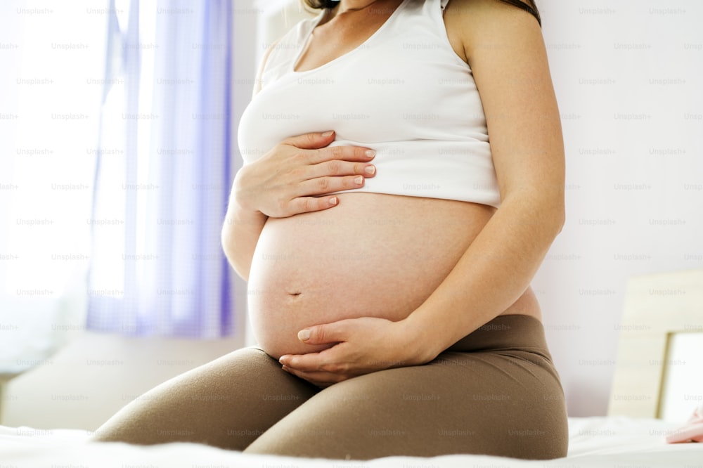 Close-up de mulher grávida irreconhecível com as mãos sobre a barriga